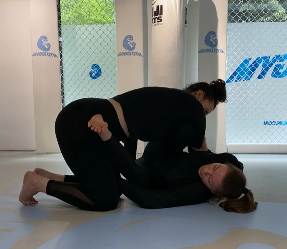 GhostGym Berlin — uma pequena academia de Mitte cujo jiu-jítsu brasileiro é uma ficha de curso de verdade, não um rótulo de navegação: `Brazilian Jiu-Jitsu` / `No-Gi Jiu-Jitsu – direkt und effektiv.` / `1 Std. 30 Min.`, com preço anexado. Ela se conta a si mesma: `01 Location` e `02 Trainers`