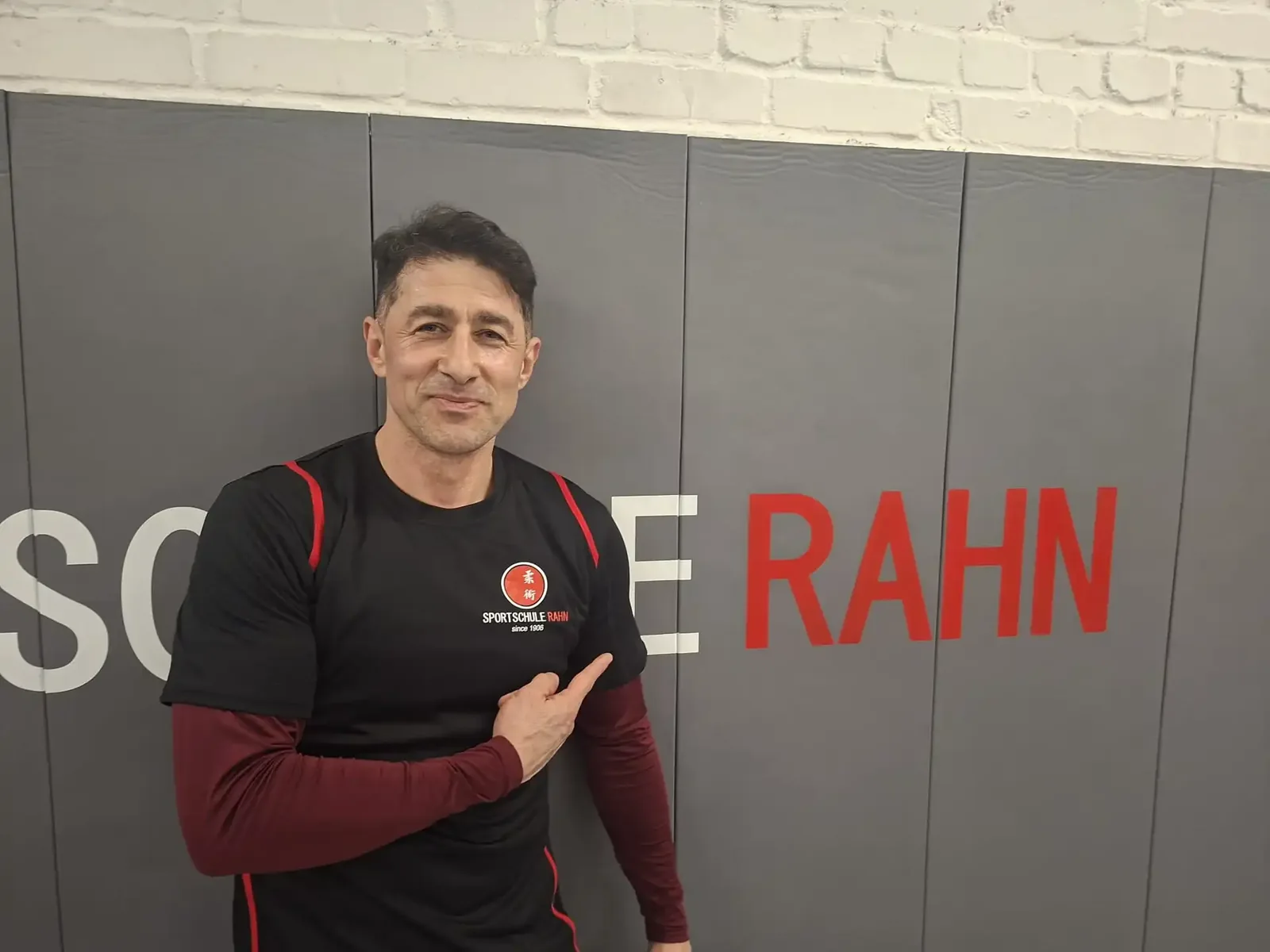 Sportschule Rahn — registered as `Jiu-Jitsu Schule R.A.H.N. GmbH`, branding itself `Kampfsport seit 1906`. The house runs `Brazilian Jiu Jitsu (BJJ)`, `Jiu-Jitsu` and `Kyusho Jitsu` as separate menu entries, so its BJJ is a real programme rather than a relabel. Its own BJJ page: `bieten Kurse im Gi … und NoGi … an. Neben Vermittlung von Bodentechniken stehen auch Würfe auf dem Stundenplan, denn BJJ Kämpfe beginnen im Stand. Am Ende einer jeden Trainingseinheit findet ein intensives Sparring statt` — Gi and No-Gi, throws as well as ground work, and hard sparring at the end of every session. ⚠ The BJJ course is `ab 14 Jahren` (14 and over)